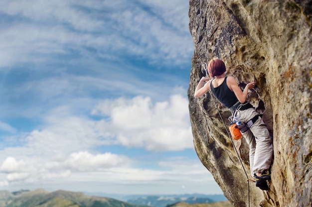 Climber climbing with rope and carbines on a big rocky wall