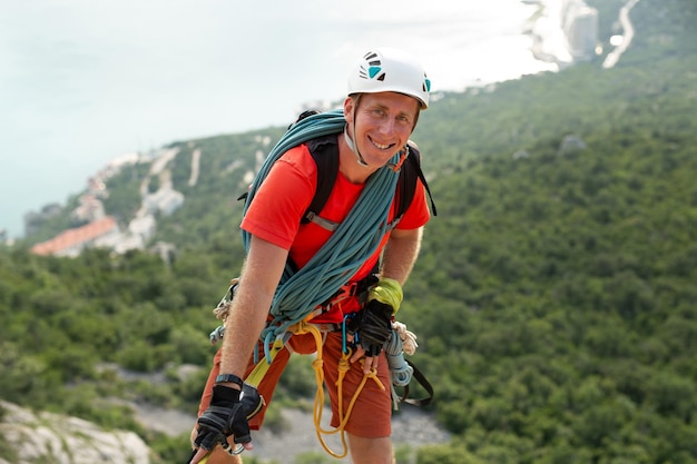 Foto lo scalatore scala la montagna su un cavo con vista sulla foresta e sul mare