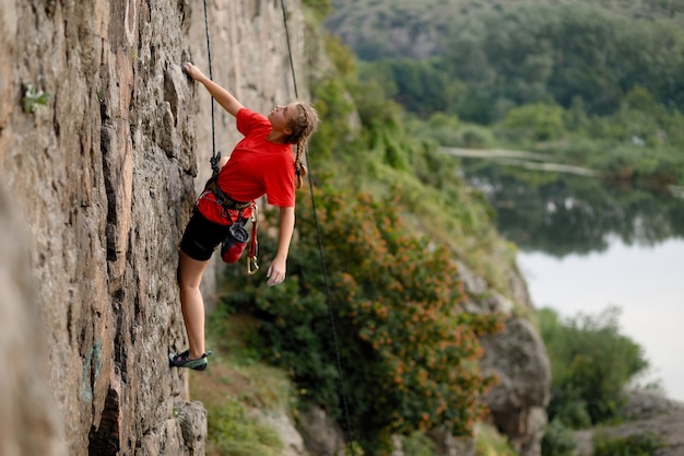 Climber overcomes challenging climbing route. a girl climbs a\
rock. woman engaged in extreme sport. extreme hobby.