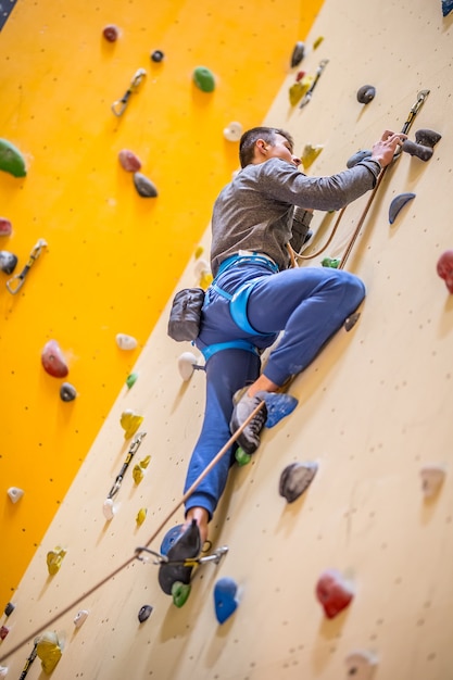 Climber on wall.Young man practicing rock climbing on a rock wall indoors.