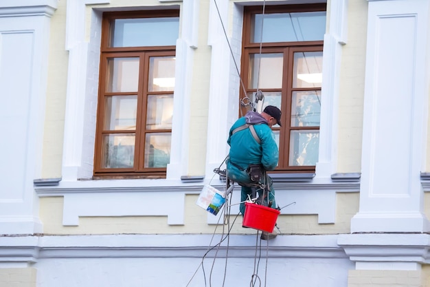 Альпинист обслуживает окно и фасад ремонтируемого жилого дома в строительной отрасли