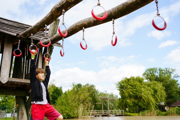 Foto ragazzo che si arrampica sul parco giochi al centro del parco nei paesi bassi