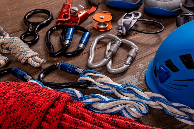 Фото Альпинистское снаряжение для альпинизма и походов, шлем, молоток, карабин, треккинговая обувь и другое на деревянном фоне, вид сверху