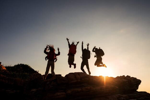 Photo climbing group friends jumping on top mountain and amazing sunset sky .