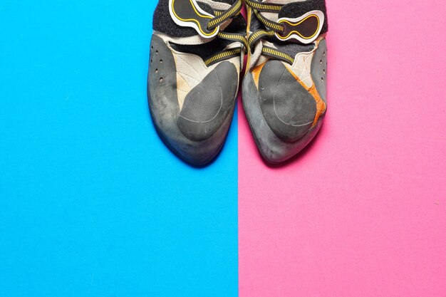 Climbing shoes on a blue and pink colorful background with copy
space flat lay. top view