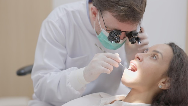 In the clinic a dentist cleans the teeth of a patient