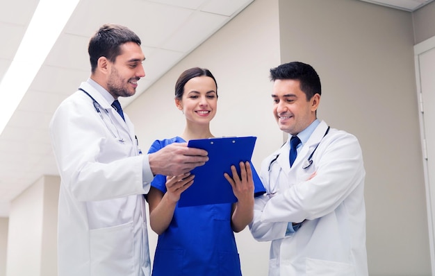 クリニック、人、ヘルスケア、医学のコンセプト – 病院の廊下でクリップボードを持つ幸せな医師や医師のグループ