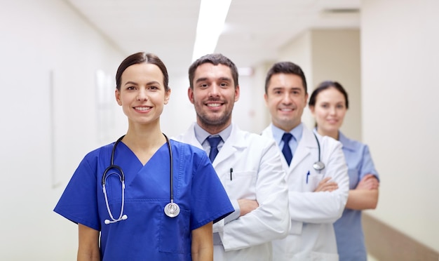 clinic, profession, people, health care and medicine concept - group of happy medics or doctors at hospital corridor