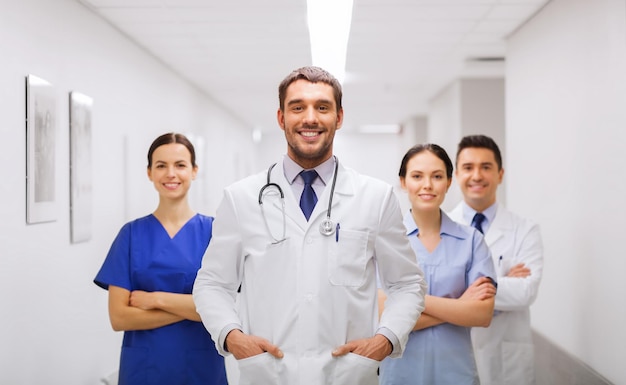 clinic, profession, people, health care and medicine concept - happy group of medics or doctors at hospital corridor