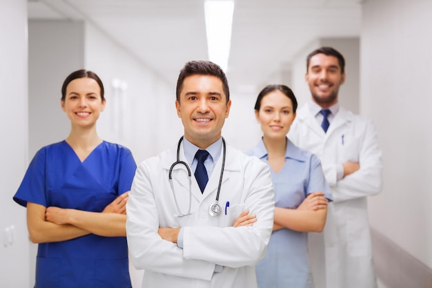 clinic, profession, people, health care and medicine concept - happy group of medics or doctors at hospital corridor