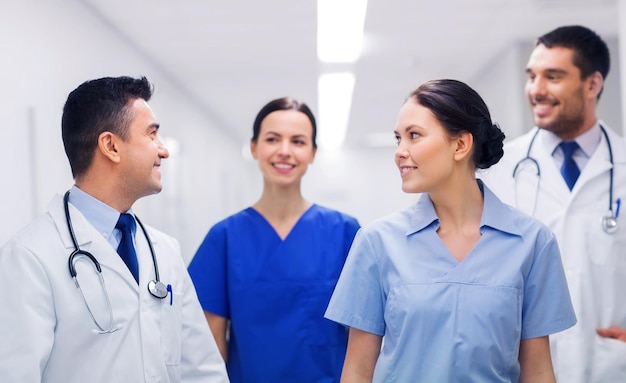 clinic, profession, people, health care and medicine concept - happy group of medics or doctors at hospital corridor