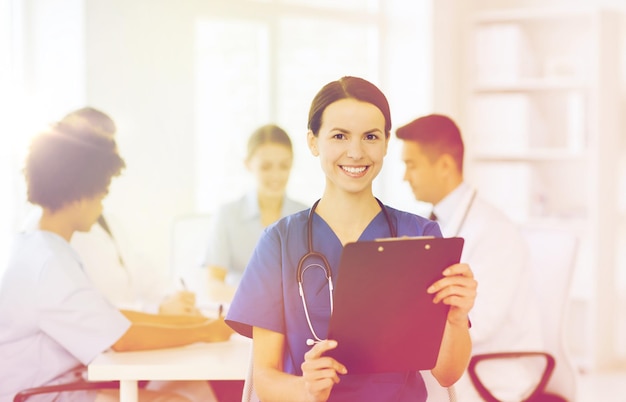 Foto concetto di clinica, professione, persone e medicina - dottoressa felice con appunti su un gruppo di medici che si incontrano in ospedale