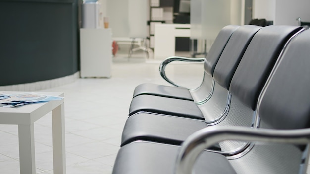 Clinical waiting area with seats in facility lobby, reception\
counter used to solve patients registration before attending\
medical appointment. empty reception counter desk in health\
center.