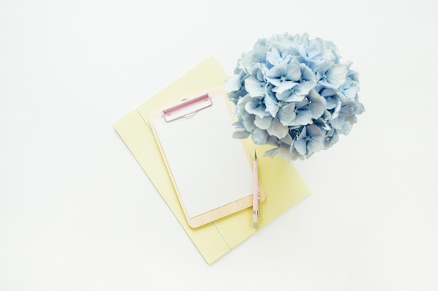 Clipboard mock up and hydrangea flowers bouquet on white surface