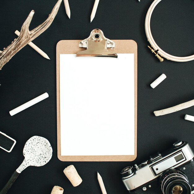 Clipboard mock up with goat horns, retro camera, handmade spoon, pencils and accessories on black chalk board