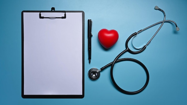 Clipboard stethoscope and red heart on blue background Healthcare and medical concept