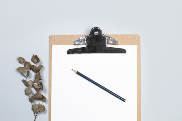 A clipboard table with paper and a pencil on a gray background