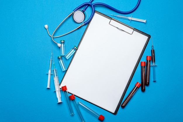 Clipboard with blank sheet of paper with medical tools on blue