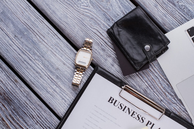 사업 계획과 고급 시계가 있는 클립보드. 흰색 나무 테이블에 사업가 액세서리입니다.