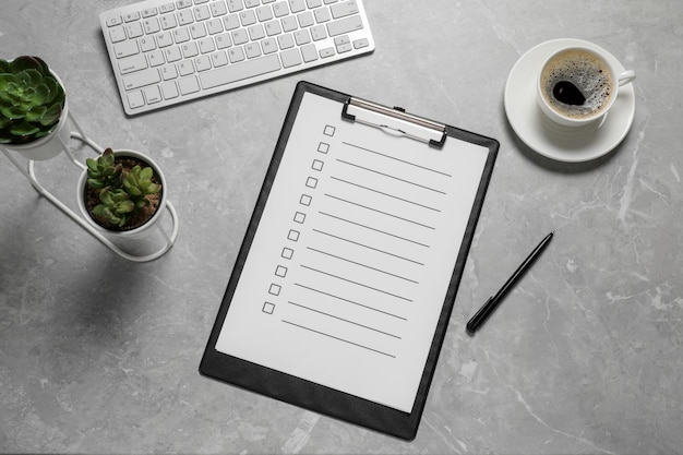 Photo clipboard with checkboxes cup of coffee plants and computer keyboard on light grey table flat lay checklist