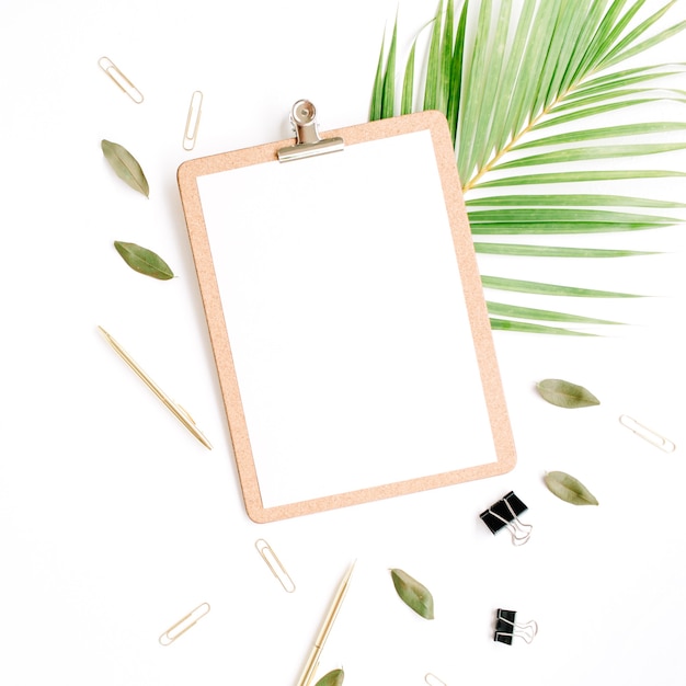 Clipboard with empty copy space blank, golden pen and clips, petals and palm branch on white background.