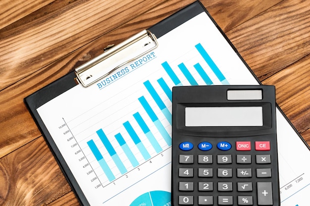 Clipboard with financial documents and calculator on the table