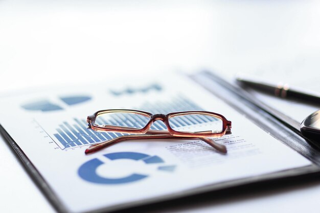 Photo clipboard with financial report and glasses on the desktop