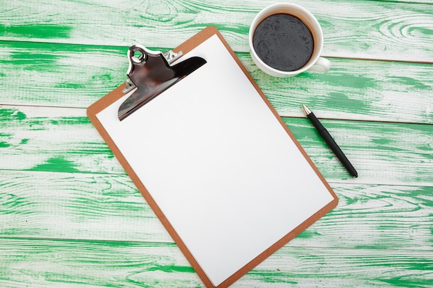 Clipboard with office supplies on green wooden table