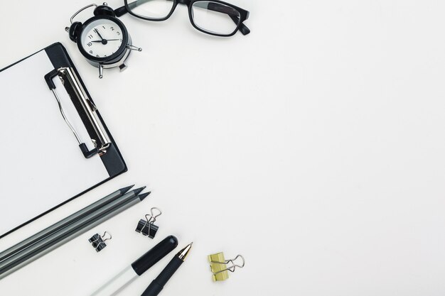 Clipboard with office supplies on white table