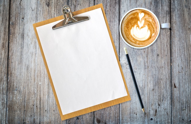 clipboard with paper pencil and coffee on table