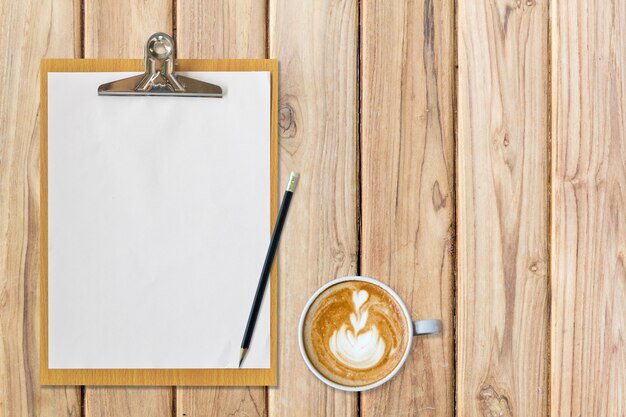 clipboard with paper pencil and coffee on table