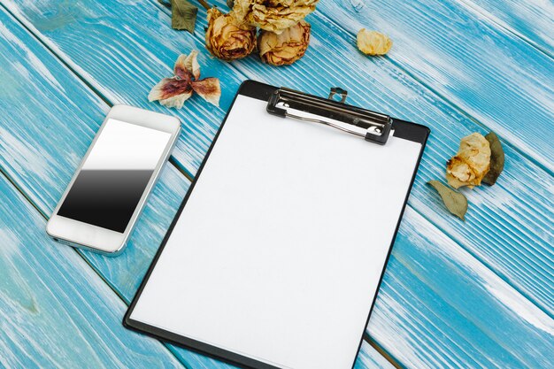 Clipboard with white blank paper on blue wooden table