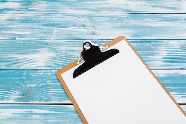 Photo clipboard with white blank paper on blue wooden table