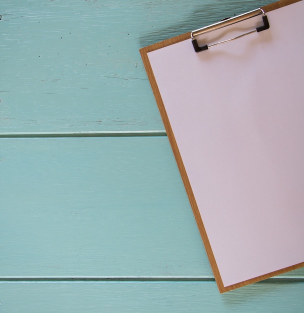 Photo clipboard with white sheet on wood background. top view.vintage style.