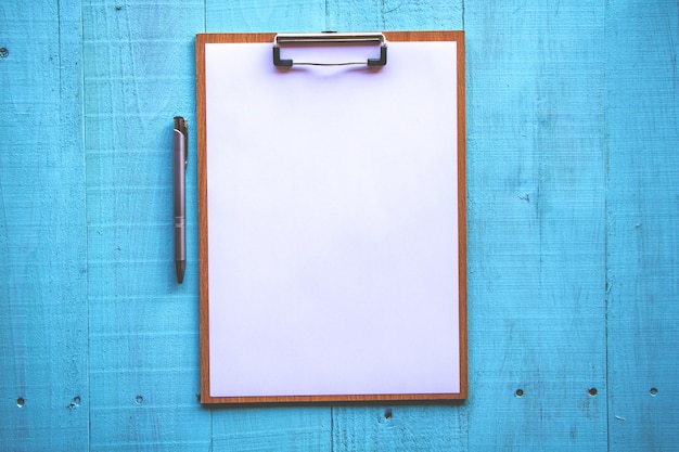 Clipboard with white sheet on wood background. 