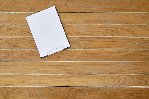 Clipboard with white sheet on wooden background