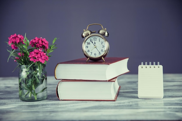 Photo clock on books with flowers