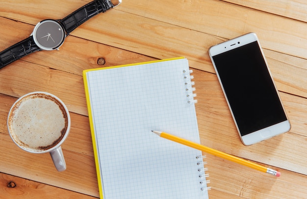 Clock, camera and notebook on a brown 