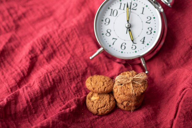 The clock and cookies place on the red fabric