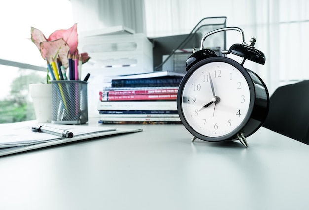 Clock on desk office with stationary in sunlight morning with colorful