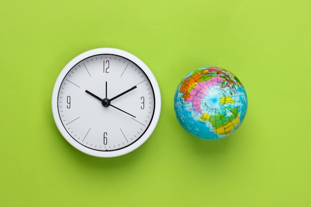 Clock and globe on a green background. World time. Top view