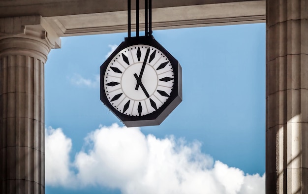 Photo clock hanging by columns against sky