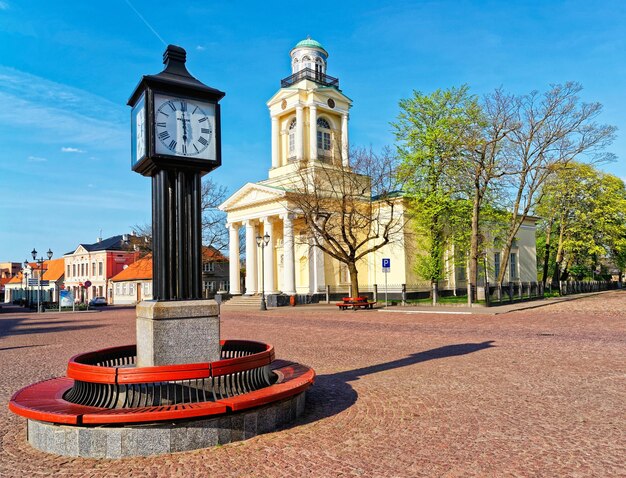 Clock and Lutheran Church of St Nicholas in Ventspils in the Town Hall Square. Ventspils is a city in the Courland region of Latvia. Latvia is a Baltic country.