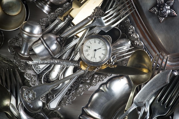 A clock on a table with forks and knives