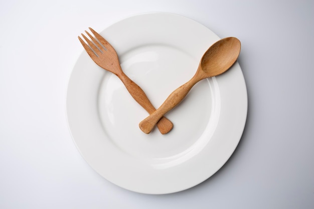 Clock white plate with wooden spoon and fork eating time meal concept