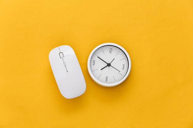 Clock with pc mouse on yellow background. Working Deadline. Top view.