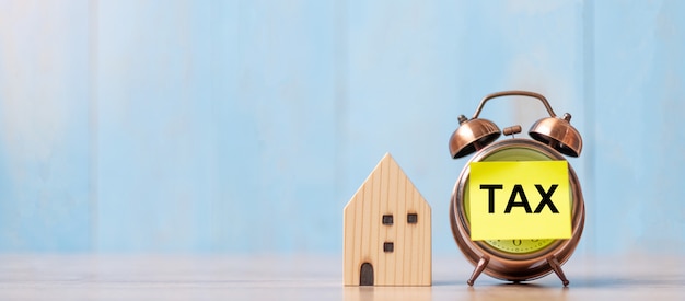 Clock with TAX text and house model on wood