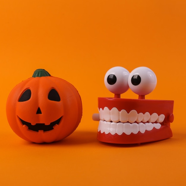 Photo clockwork jaw with pumpkin jack lantern head on orange background halloween decorations minimal still life photo