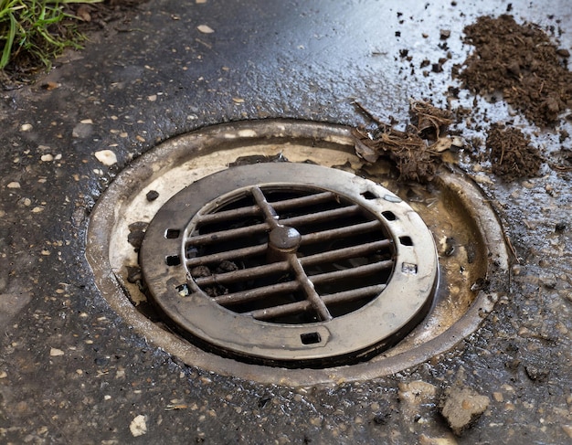 A clogged drain cover is sitting on the ground