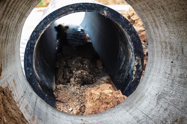 Clogged water or sewer pipes pipe cleaning underground pipeline\
works repair work on the pipeline underground communications water\
supply at home view from the big pipe